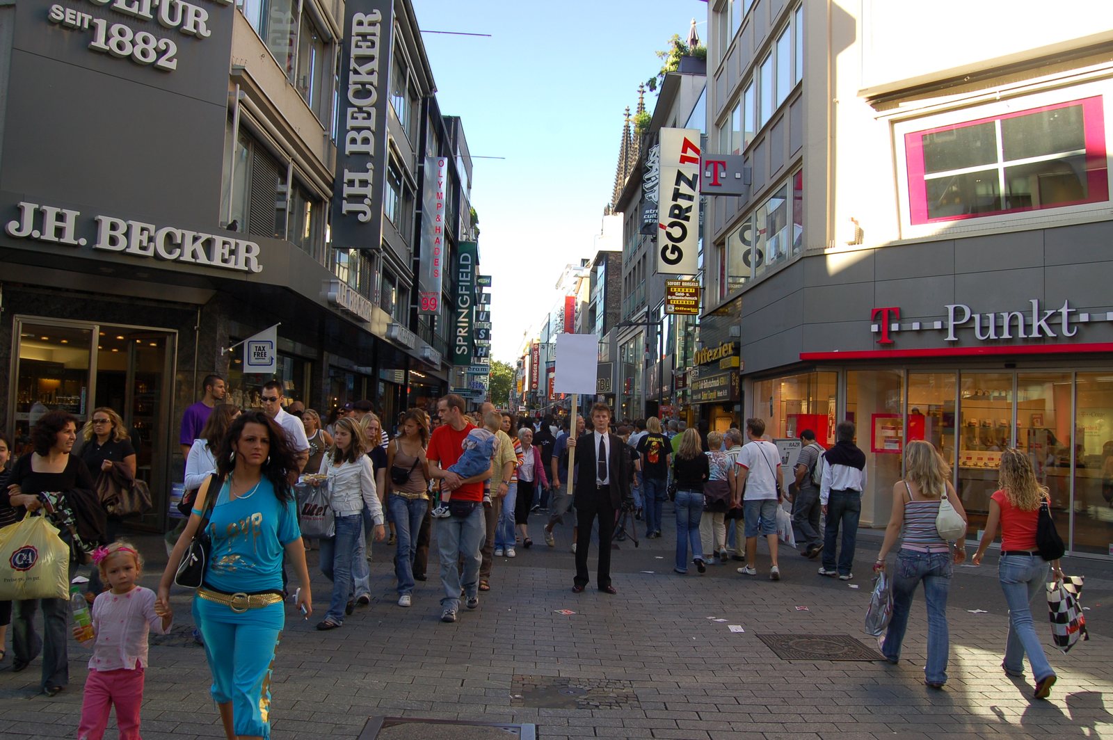 The suited figure with the blank sign in the crowd