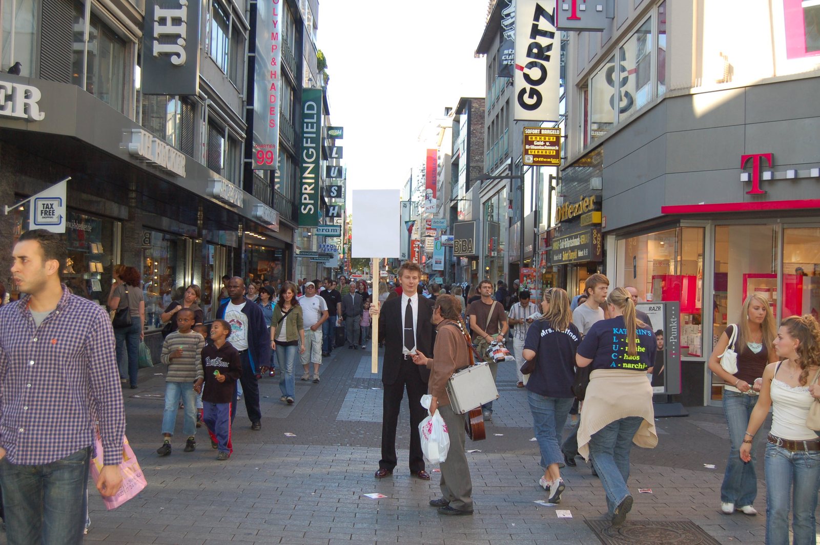 The suited figure with the blank sign in the crowd of the shopping street
